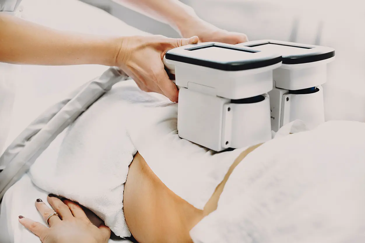 A technician uses specialized cryo-slimming equipment on a client's stomach during a treatment session.
